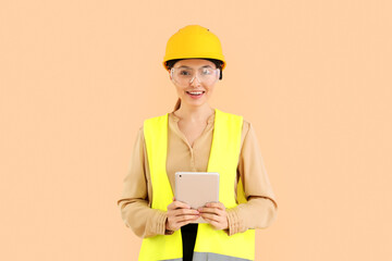 Female engineer in vest and with tablet computer on beige background