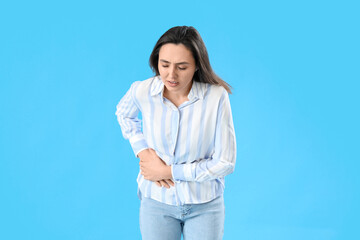 Young woman with appendicitis on blue background