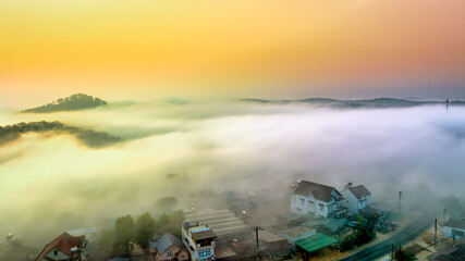 Fototapeta premium Aerial view of Xuan Tho suburbs near Da Lat city at morning with misty and sunrise sky. This place is considered most beautiful and peaceful place to watch sunrise in highlands of Vietnam