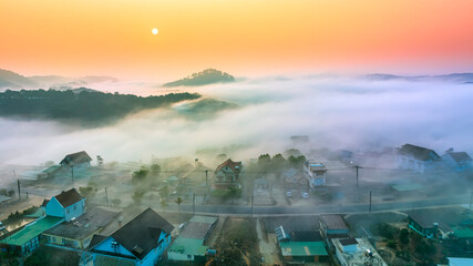 Fototapeta premium Aerial view of Xuan Tho suburbs near Da Lat city at morning with misty and sunrise sky. This place is considered most beautiful and peaceful place to watch sunrise in highlands of Vietnam
