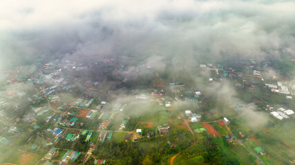 Aerial view of Bao Loc cityscape at morning with misty sky in Vietnam highlands. Urban development texture, transport infrastructure and green parks