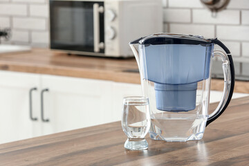 Modern filter jug and glass of water on kitchen counter