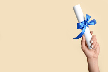 Woman holding diploma with ribbon on yellow background
