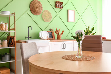 Vase with beautiful flowers on table in modern kitchen