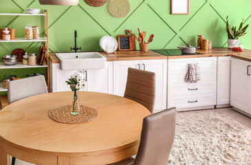 Interior of modern kitchen with white counters and flower vase on table