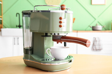 Modern coffee machine with cup on wooden table in kitchen