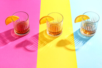 Glasses of rum with orange slices on colorful background