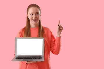 Female programmer with laptop pointing at something on pink background