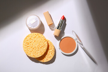 Set of decorative cosmetics and sponges on light background
