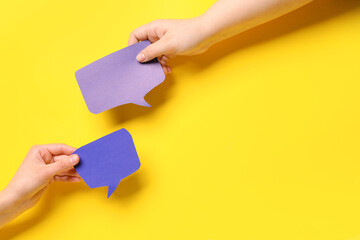 Women holding blank speech bubbles on yellow background