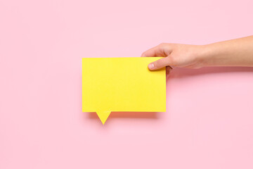Woman holding blank speech bubble on pink background