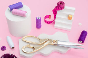 Podiums with tailor's supplies on pink background
