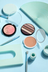 Decorative cosmetics with brushes and podiums on blue background