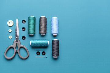 Fototapeta premium Composition with thread spools, buttons and scissors on color background