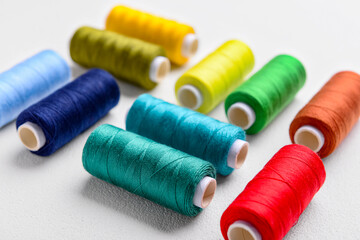 Composition with colorful thread spools on light background, closeup