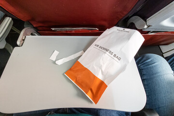 Used air sickness paper bag on table inside airplane cabin