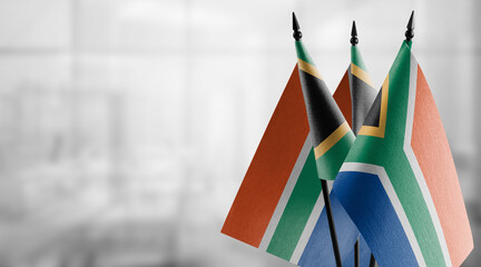 Small flags of the South Africa on an abstract blurry background