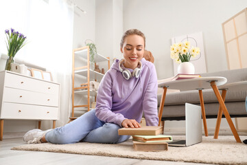 Female student with books and laptop at home