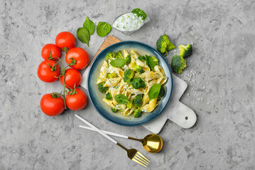 Plate with tasty pasta and broccoli on grey grunge background