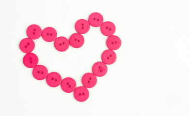 Shape of heart from pink buttons on a white background. Symbol of love