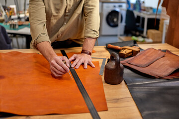 Sewing process of the leather belt. Man's hands behind sewing. Leather workshop.close up cropped shot, free time, spare time, lifestyle