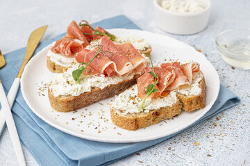 Plate of tasty bruschettas with jamon on light background