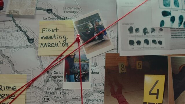 Photo of killed victim, sticky notes, map, fingerprints and pictures of suspects pinned to investigation board and linked with red thread. CSI concept, close-up shot