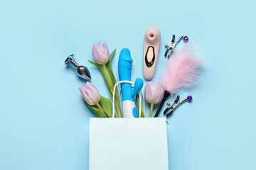 Paper bag with sex toys and tulips on blue background