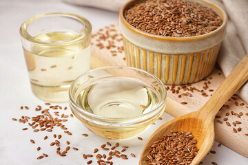 Bowl, glass with flax oil and spoon of seeds on white background
