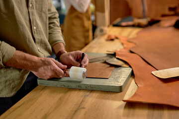 professional craftsmana using Mallets and Chisels to create leather brand, close up cropped photo
