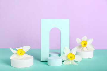 Decorative plaster podiums with flowers on turquoise table against violet background