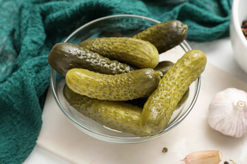 Bowl with tasty fermented cucumbers on light background