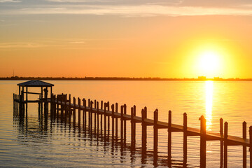 Fototapeta na wymiar Long wooden dock at sunrise along the Indian River Lagoon in Brevard County, Florida