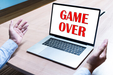 Businessman spread out your hands with message GAME OVER on display laptop
