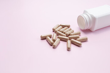 Scattered Softgel Capsules OF Slippery Elm, White Bottle, Container On Pink Background. Dietary Nutritional Supplement, Medication. Ulmus Fulva, Herbal Remedy Concept. Horizontal, Copy space For Text