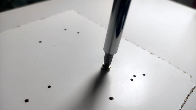 The master twists a screw into a wooden plate with a screwdriver