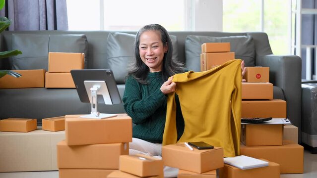 Senior Asian business owner woman prepare parcel box and standing check online orders for deliver to customer on tablet, laptop Shopping Online concept..