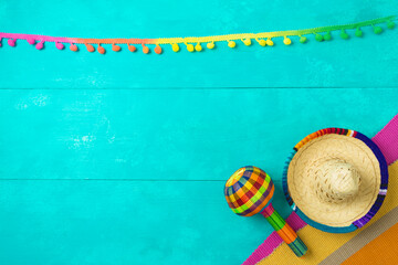 Mexican party decorations with sombrero hat and maracas on blue wooden background. Cinco de Mayo holiday celebration. Top view from above
