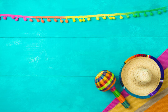 Mexican party decorations with sombrero hat and maracas on blue wooden background. Cinco de Mayo holiday celebration. Top view from above