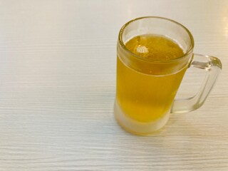 a glass of freshly chilled beer put on a white table under a warm light with copy space on the left side of the frame
