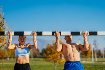 Sporty couple doing pull ups together