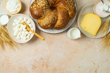Jewish holiday Shavuot concept with challah bread, milk and cheese on stone table background. Top view from above