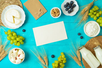 Jewish holiday Shavuot greeting card mock up with cheese, milk bottle and wheat ears on wooden blue table background. Top view from above