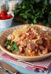 Braised cabbage with rice and sausages in a plate on a blue background, Close up
