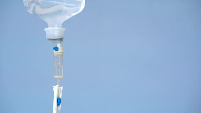 Closeup of IV loading dose in hospital with blue background, Intravenous saline solution.