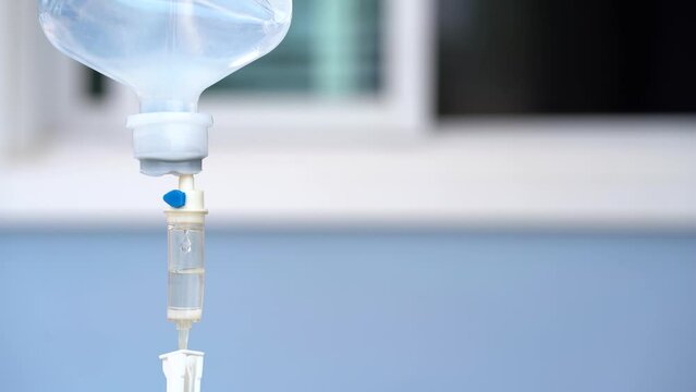 Closeup of IV in hospital with blue background, Intravenous saline solution.