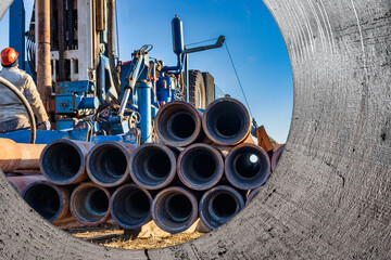Pipes for a well close-up. Powerful drilling rig against a cloudy sky. Drilling of deep wells....