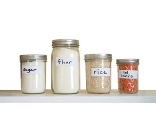 Sugar flour rice and red lentils in glassware storage on wooden shelf isolated on white
