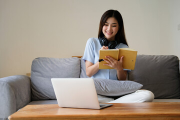 Focused asian woman taking notes while working remotely