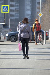 A woman walks along the sidewalk on a spring morning